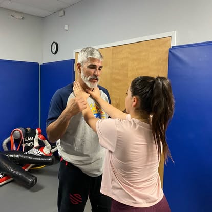 A student drilling a two-handed collar grab defense with the instructor during a women’s self-defense class