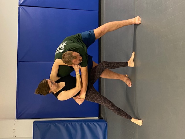 Two students working a standing arm control and takedown drill on the mats